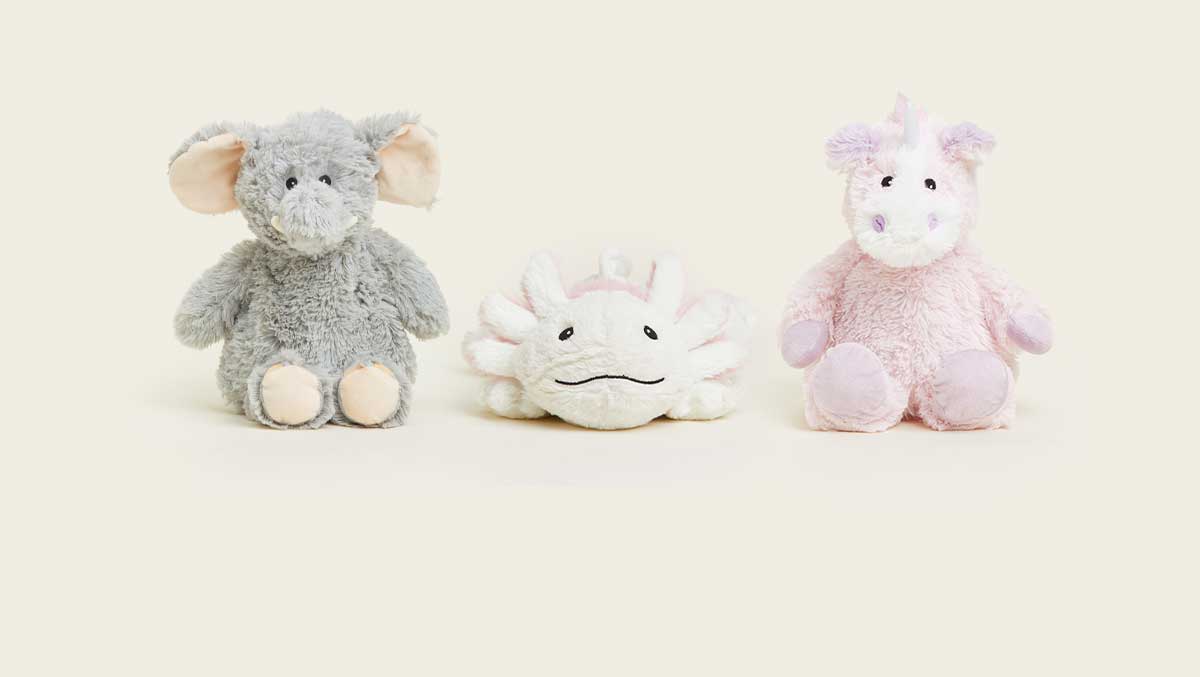 Gray Elephant Warmies, Axolotly Warmies, and Pink Unicorn Warmies sitting in a row