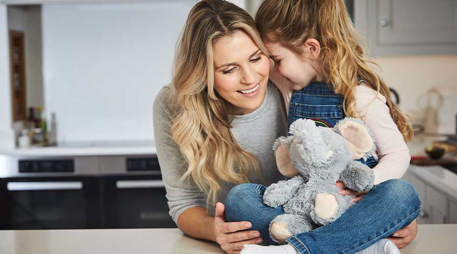 Mother and daughter smiling while holding a Gray Elephant Warmies.