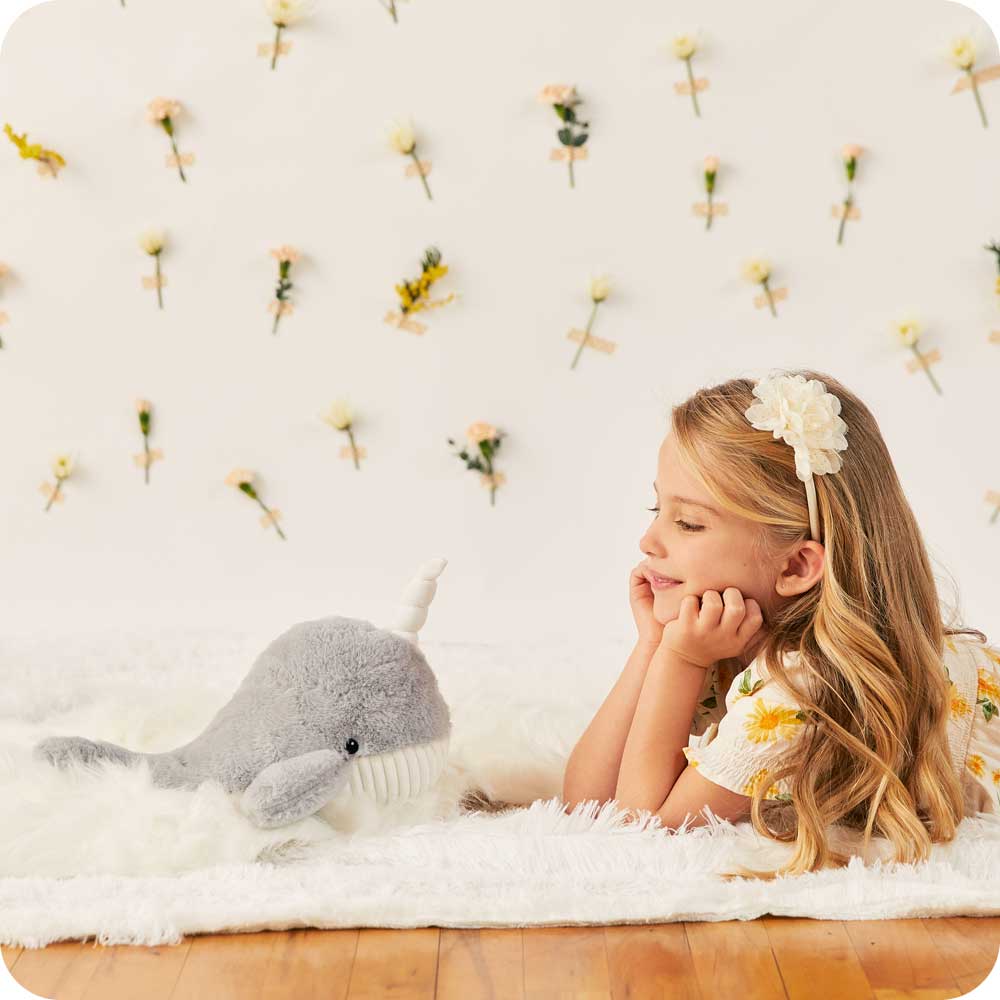 Little girl smiling at Soft Warm Weighted Narwhal Plush Warmies