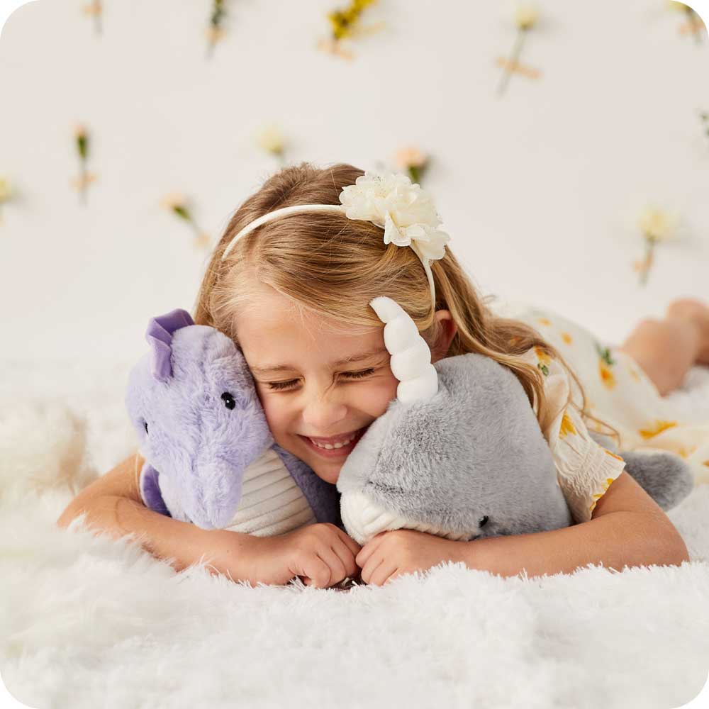 Child laying down and cuddling a Soft Warm Weighted Seahorse Plush Warmies