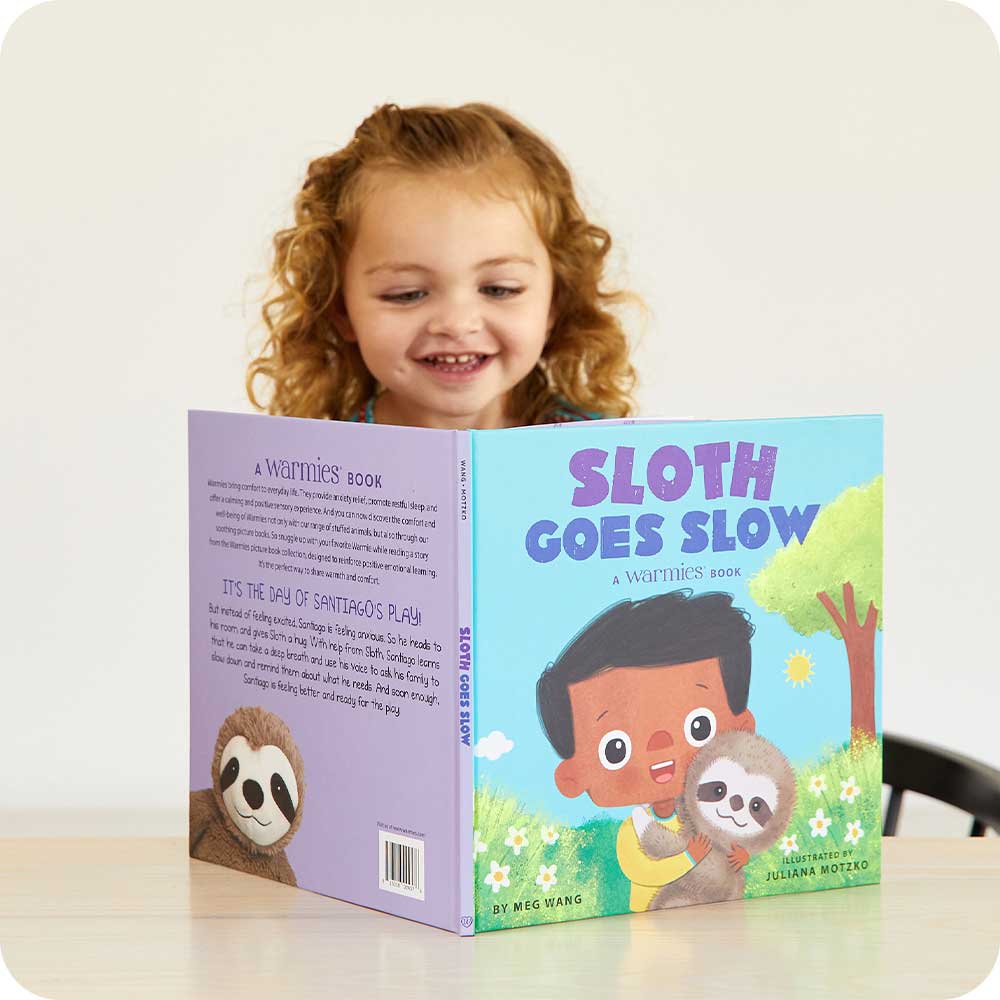 Toddler smiling while reading Sloth Goes Slow Book - Warmies USA